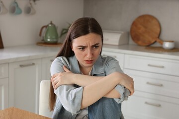 Worried woman suffering from paranoia in kitchen