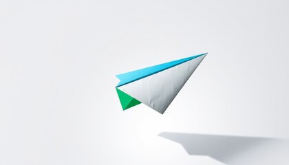 Blue green and grey paper airplane floating in air with shadow on white background