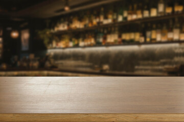 Blurred atmospheric bar with empty wooden table in the foreground, ideal for product display or...