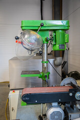 Green bench drill press and belt sander in workshop
