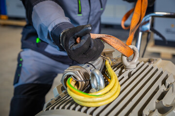 Worker securing electric motor with lifting sling for transportation