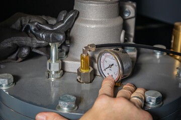 Technician adjusting pressure gauge on industrial equipment