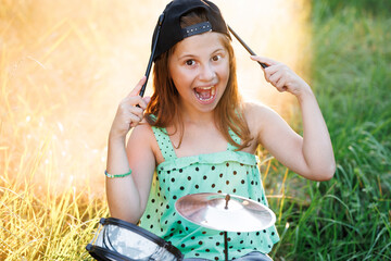 Cheerful little girl with drums. Emotional portrait of happy little girl shows her tongue with drum...