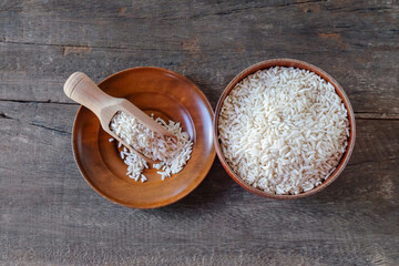 Pile of rice in a bowl with a wood spoon on table.