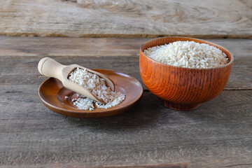Pile of rice in a bowl with a wood spoon on table.