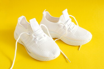 White summer sneakers stand on a yellow background.