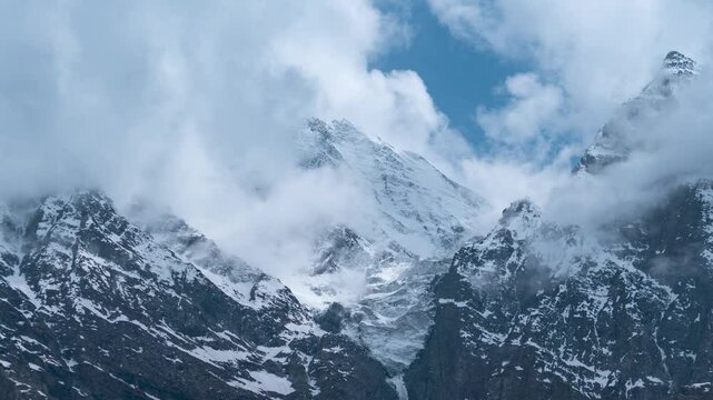 4K Zoom In time lapse shot of dark monsoon clouds covering the snowy glacier on a mountain peak during the monsoon season as seen from Khangsar village in Lahaul Valley, Himachal Pradesh, India.
