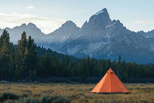 Sunrise in mountains, orange tent in meadow
