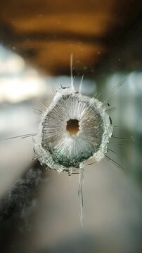 Bullet hole in glass showcasing aftermath of gunfire at urban location with clear details