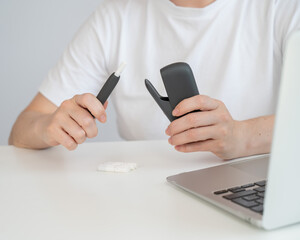 A woman takes a tobacco heating system out of a charger. Electronic cigarette.