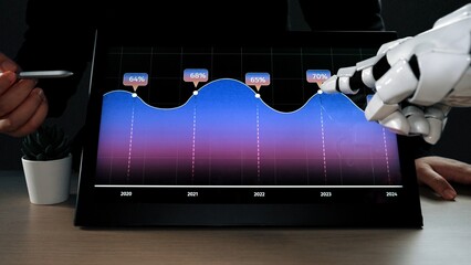 A futuristic robotic hand interacts with a touchscreen display showcasing data trends and...