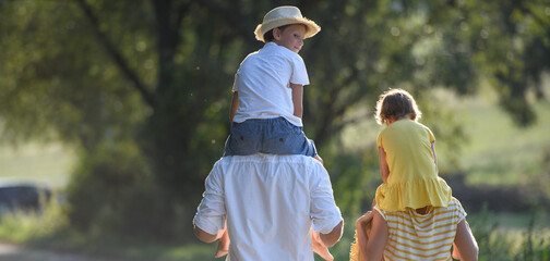 Banner with copy space. Parents carrying two kids on shoulders.