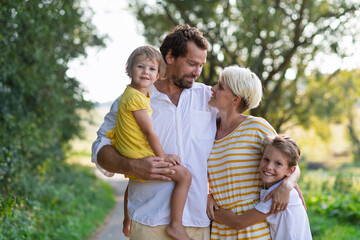 A portrait of young family with small children in sunny summer nature.