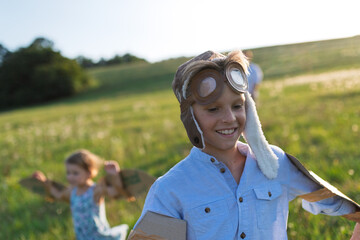 Siblings dressed as pilots running through a sunny field.