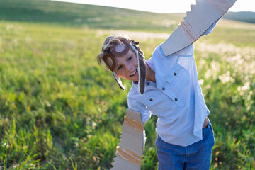Child playing aviator in nature with wings and goggles.