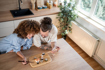 Happy couple enjoying sushi together in modern kitchen
