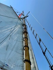 Upward view of classic wooden sailboat mast and rigging against clear summer sky - Coastal Escape Series