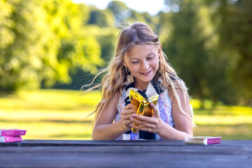 Joyful young girl unwrapping Dubai chocolate in nature on a wooden table at sunset. Laughing woman with angel chocolate gift