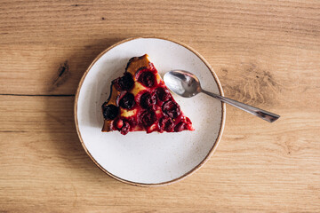 Slice of a homemade cherry pie on wooden table, top view.