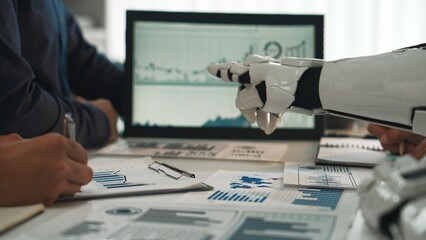 A robot collaborates with humans in a modern office, focusing on data analysis. Graphical...