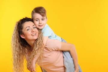 Family. Happy mother and her son on yellow background. Space for text