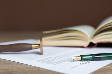 Notary document and fountain pen on wooden table against brown background, selective focus
