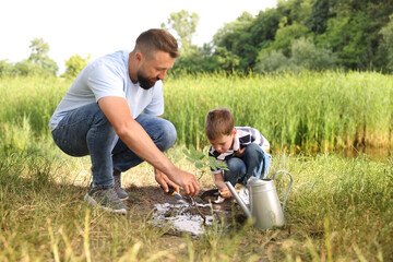 Father and his son planting tree into soil outdoors
