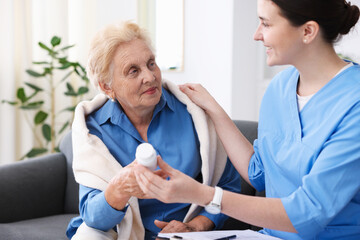 Obraz premium Nurse giving pills to senior woman indoors. Home health care service