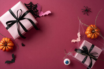 Pink wrapped gifts, black ribbons, pumpkins, bats, and Halloween icons on festive purple