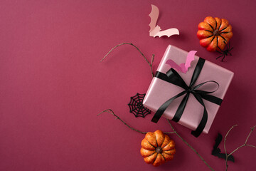 Pink gift box tied with black ribbon, surrounded by fake pumpkins, bats, and cobwebs