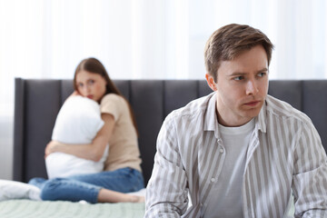 Woman and man having quarrel on bed at home, selective focus