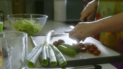 Woman standing in domestic modern home kitchen preparing healthy vegetable salad enjoy process....