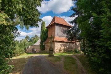 Picturesque wooden church, sunny cemetery. Historic Czech rural idyll.