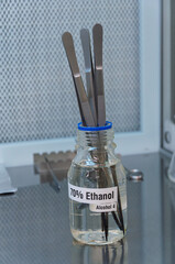 Laboratory tweezers in ethanol jar inside laminar flow hood. Ideal for pharmaceutical brochures,...
