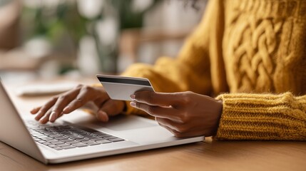 Close up of black girl hold bank credit card and type on laptop, shopping online using computer, buying goods or ordering online, entering bank accounts and details in online banking offer