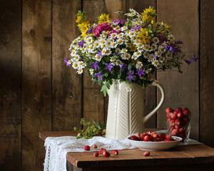 Wildflowers bouquet and strawberries creating a rustic still life