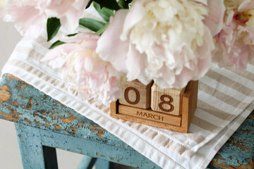 Pink peonies and wooden calendar showing 8 march, international women's day