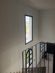 Modern staircase with sleek black railing, bright window illuminating the space, minimalist design...