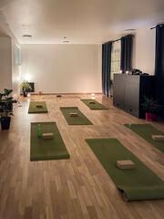 Yoga studio interior featuring green mats, wooden flooring, blocks, and plants, creating a serene...