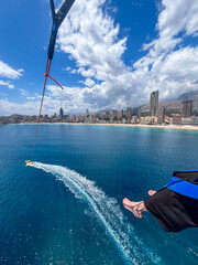 Benidorm, Spain - May 12, 2025: Midlife woman paragliding over the stunning coastline of Benidorm,...