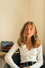 Young woman sitting in a modern workspace with laptop in a bright room