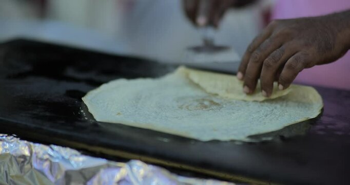 Indian caterers preparing fresh uttapam and crispy dosa on a hot tawa during a live food counter at a festive event