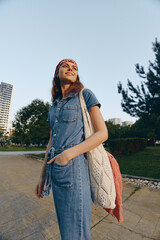 lifestyle woman in modern boho-western denim street style with a knitted tote bag, smiling outdoors...
