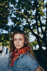 Lifestyle woman in modern boho-western denim street style with red bandana, natural light and film...