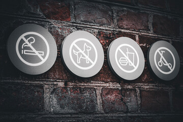 Set of four prohibition signs on brick wall no smoking no dogs no food or drink no scooters 