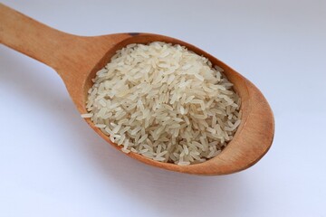 White rice in a wooden spoon on white background, close-up — concept of natural nutrition, visual purity and culinary simplicity for healthy lifestyle