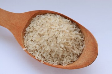 White rice in a wooden spoon on white background, close-up — concept of natural nutrition, visual purity and culinary simplicity for healthy lifestyle