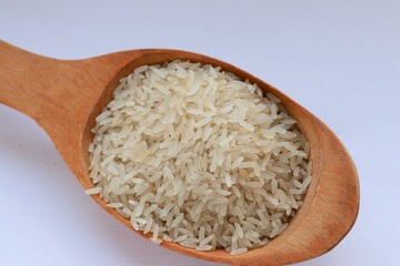 White rice in a wooden spoon on white background, close-up — concept of natural nutrition, visual purity and culinary simplicity for healthy lifestyle