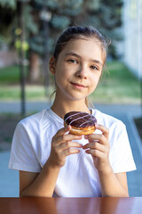 Portrait of a young girl enjoying a chocolate donut in a park