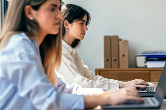 Two beautiful designer women working together with laptop in the office